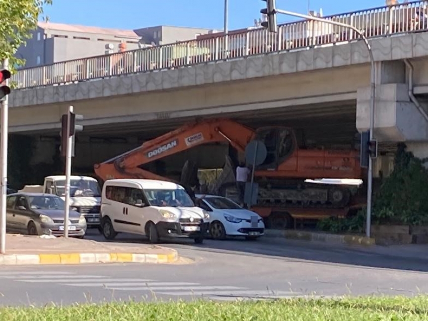 Tırın dorsesinde taşınan iş makinesi köprülü kavşakta üst geçide sıkıştı